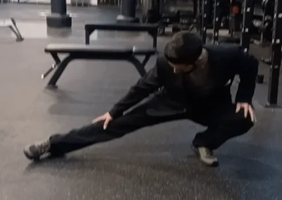 Man lunging in black tactical stretch suit in gym at Stych Inc, Oxnard tactical gear shop.