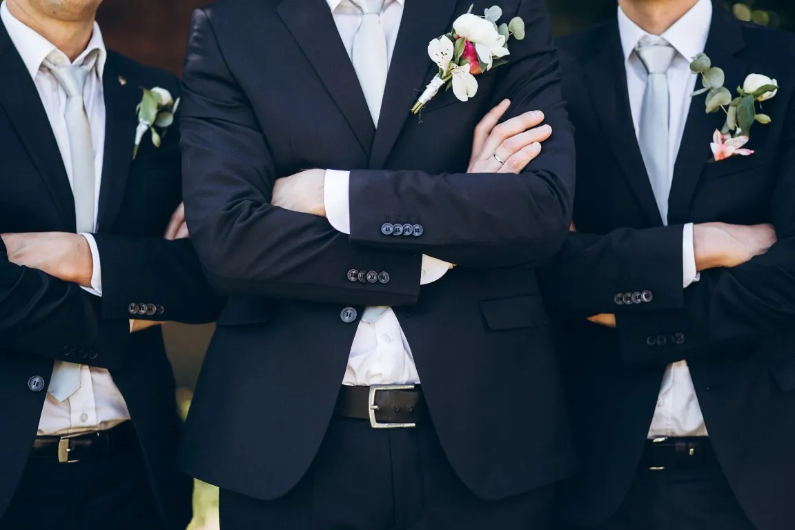 A young man in a suit places a corsage on the wrist of a young woman wearing her prom dress.