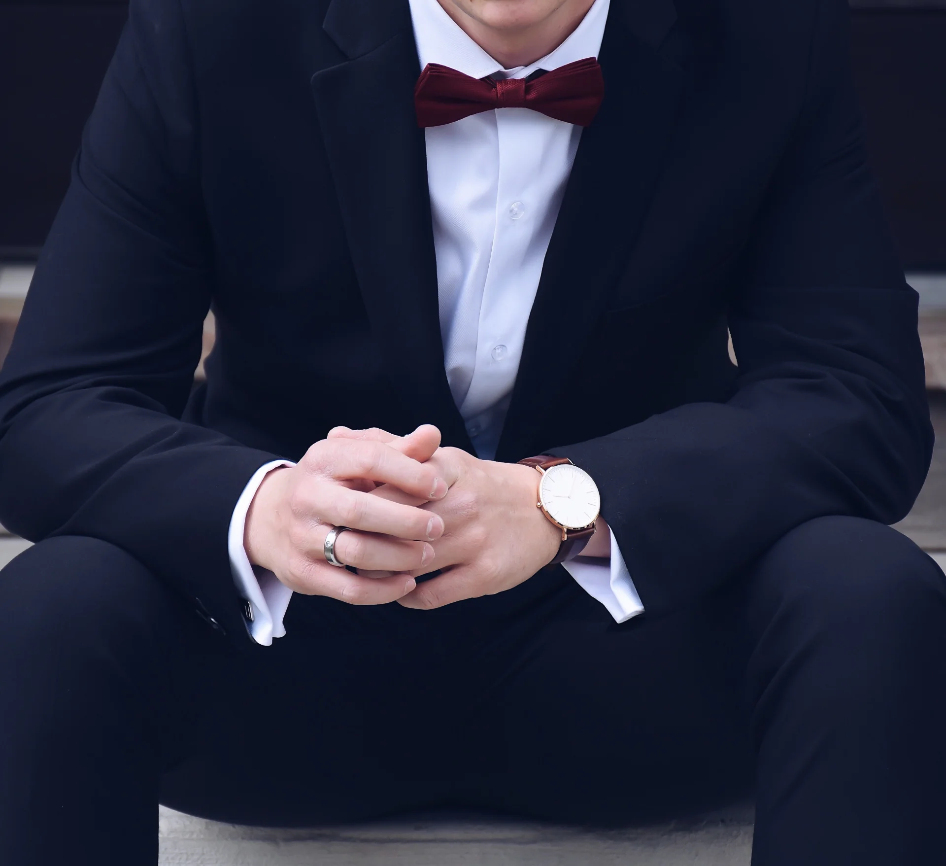 Young man wearing a dark formal suit with a burgundy bow tie for prom